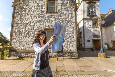 Female tourist with map standing in city