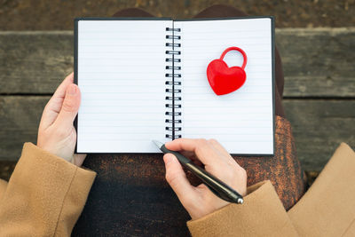 Low section of woman writing in spiral notebook