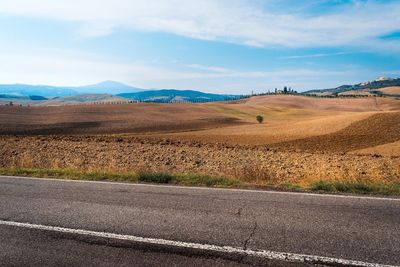 Empty road by land against sky