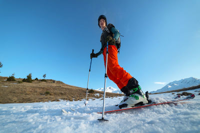 Man skiing on snowcapped mountain against clear sky