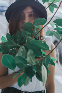 Portrait of young woman standing by plants