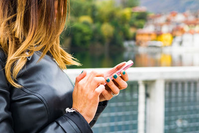 Close-up of woman using mobile phone on bridge