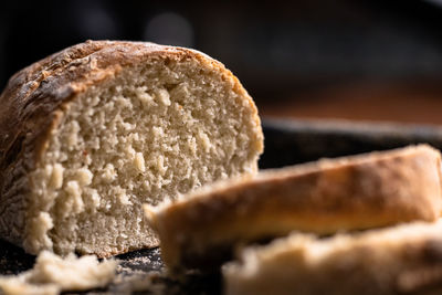 Baked homemade bread on black and wooden background, bakery setting.