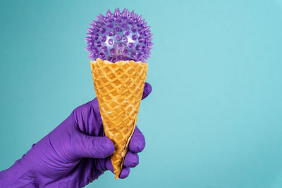 Person holding ice cream against blue background
