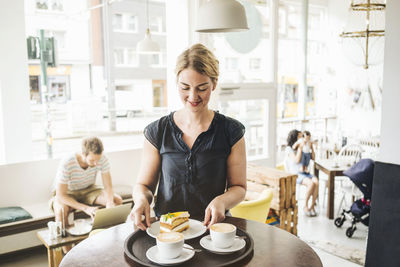 Waitress in a cafe serving cake and coffee