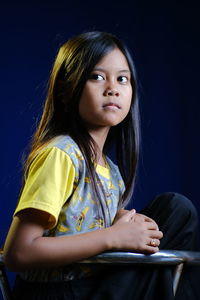 Girl sitting against black background