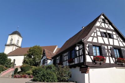 Low angle view of trees and building against clear blue sky