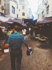 Rear view of people standing at market in city