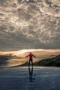 Rear view of man standing on mountain against sky