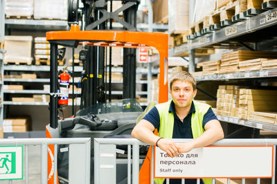 Worker standing by forklift in factory