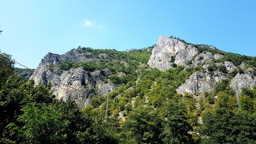 Low angle view of rocks against clear blue sky