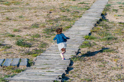 Full length of girl running on boardwalk
