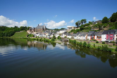 Scenic view of river by buildings against sky