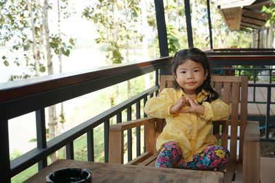 Portrait of girl sitting on wooden chair