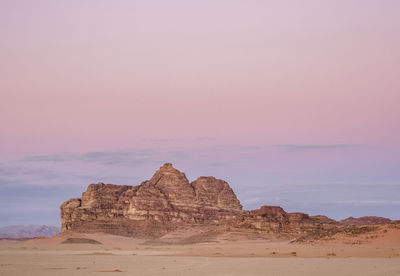 Rock formation in desert against sky during sunset