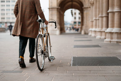 Midsection close up leg shot of a businessman with bicycle commuting to the office. historical area