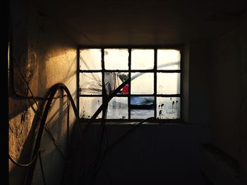 Old electric cables against broken window in abandoned room