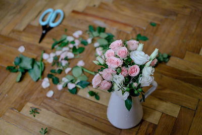 High angle view of roses in vase on hardwood floor 