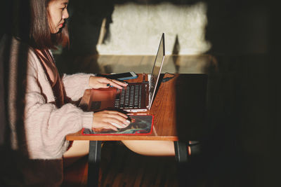 Side view of man using mobile phone at home