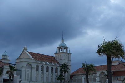 Low angle view of palm trees and buildings against sky