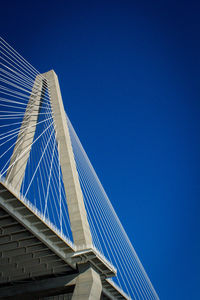 Low angle view of suspension bridge against clear blue sky