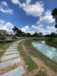 Footpath by canal against sky