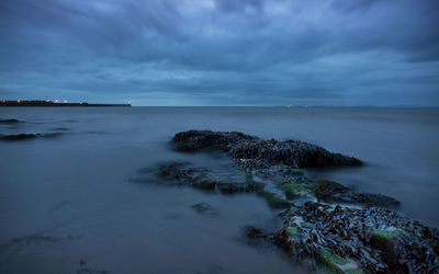 Scenic view of sea against cloudy sky at dusk