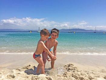 Two little kids playing with the sand in a beach. island beach in the north of spain