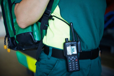 Midsection of female paramedic with walkie-talkie on belt in parking lot