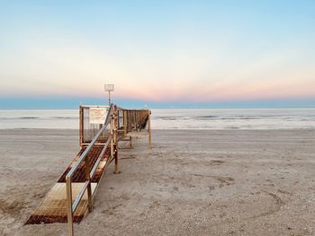 Lifeguard hut on beach against sky during sunset