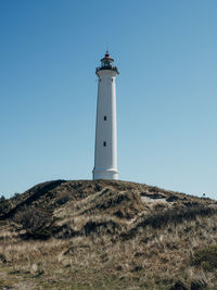 Low angle view of lighthouse on field against sky