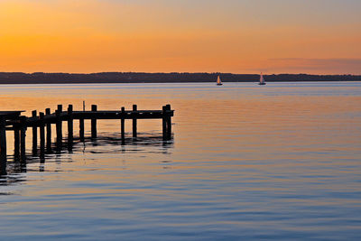 Pier over lake against sky during sunset