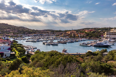 Boats moored in sea by town against sky