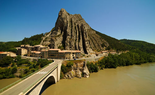 High angle view of bridge and mountain by river against clear sky