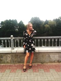 Full length of woman standing on railing against trees