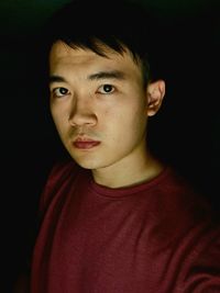 Portrait of young man against black background