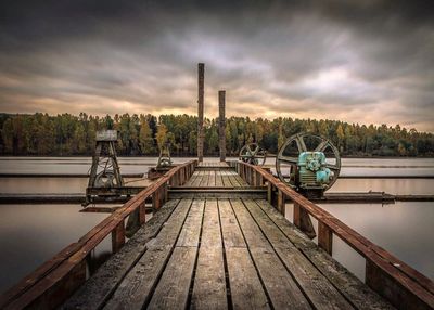 Jetty by lake against sky during sunset