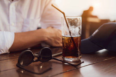 Midsection of man holding beer glass on table