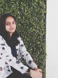 Portrait of smiling young woman standing against plants