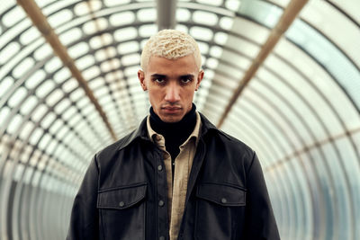 Portrait of young man with blond hair standing in tunnel