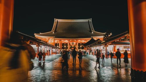 People at illuminated building in city at night