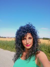 Portrait of smiling woman standing against blue sky