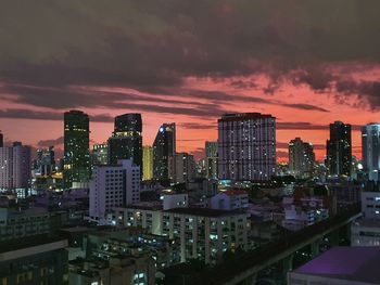 Illuminated buildings in city against sky during sunset