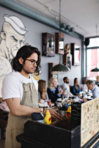 Young owner standing in lectern while customers having brunch