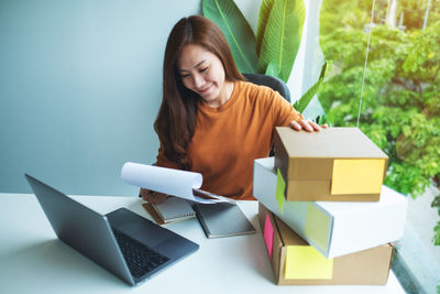 Portrait of young woman using digital tablet while sitting on table