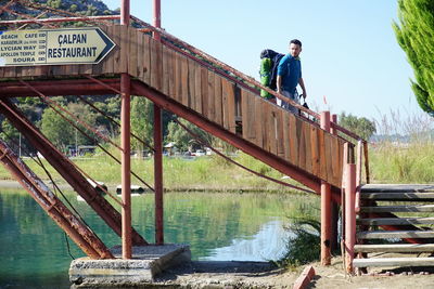 Man standing on footbridge over lake