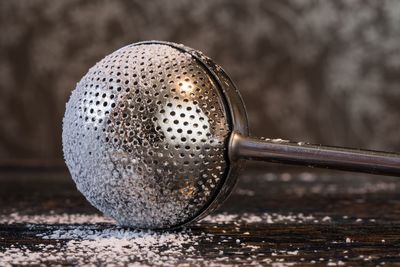 Close-up of sugar duster with powdered sugar on wooden table