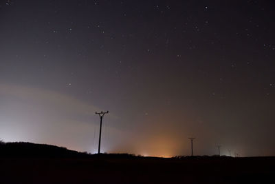 Low angle view of silhouette windmills against sky at night
