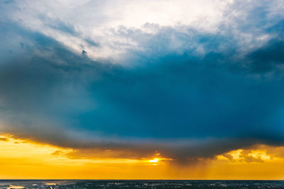 Scenic view of sea against dramatic sky during sunset