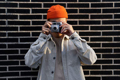 Midsection of man photographing against wall